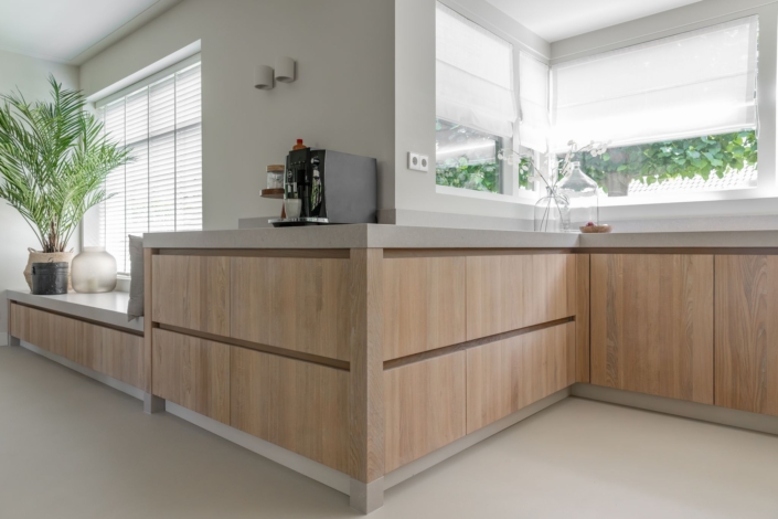 japandi-keuken-op-maat-eiken-composiet-07.jpg Hoek van de keuken met eiken fronten, composiet werkblad en raamlicht op het werkvlak.