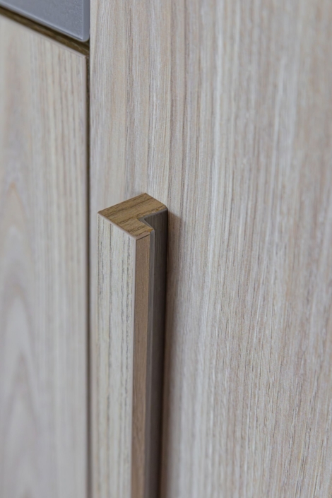 Detail van houten greep in houtlook materiaal met doorlopende nerf in maatwerkkeuken