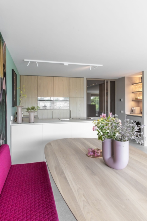 Moderne maatwerkkeuken met greige kookeiland en houtlook kastenwand in Schoonhoven